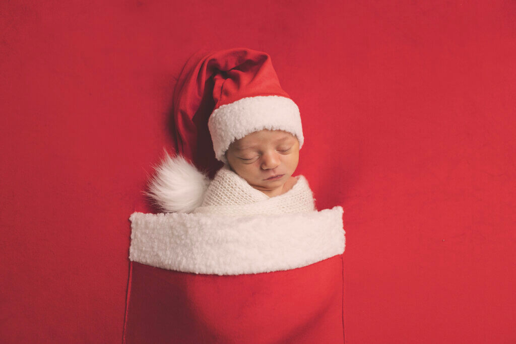Newborn baby dressed in a Santa outfit during a holiday-themed newborn photography session in Pawtucket, Rhode Island.