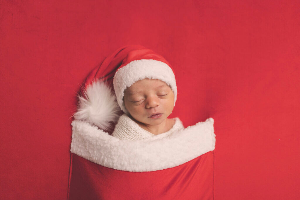Newborn baby dressed in a Santa outfit during a holiday-themed newborn