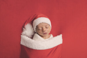 Newborn baby dressed in a Santa outfit during a holiday-themed newborn
