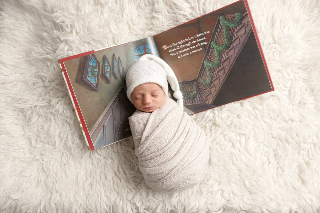 Newborn baby peacefully sleeping, wrapped in a white knit swaddle during a studio newborn photography session in Pawtucket, Rhode Island.