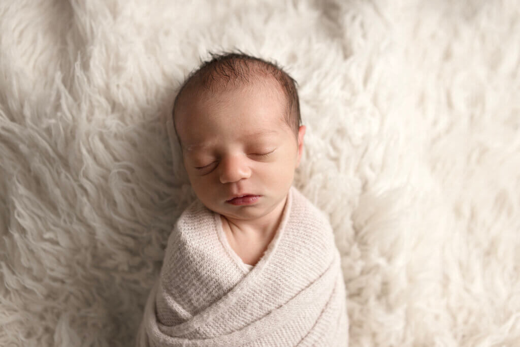 sleeping newborn swaddled on fur backdrop in photography studio in Pawtucket, RI