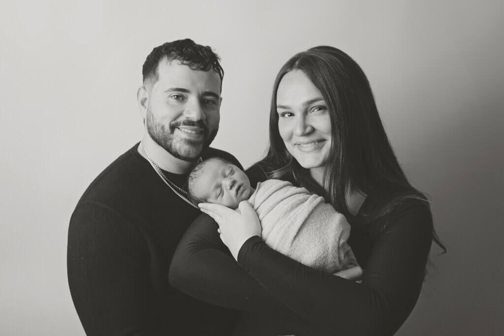 Mom and dad posing with their newborn baby boy