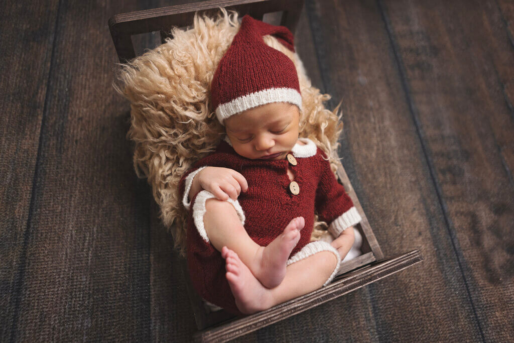 Newborn baby dressed in a Santa outfit during a holiday-themed newborn photography session in Pawtucket, Rhode Island.