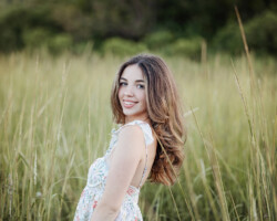 High school senior girl posing on the beach in Rhode Island during sunset, wearing a flowy dress.