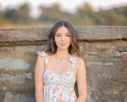 High school senior girl posing on the beach in Rhode Island during sunset, wearing a flowy dress.