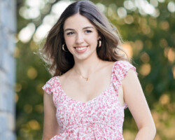High school senior girl posing on the beach in Rhode Island during sunset, wearing a flowy dress.
